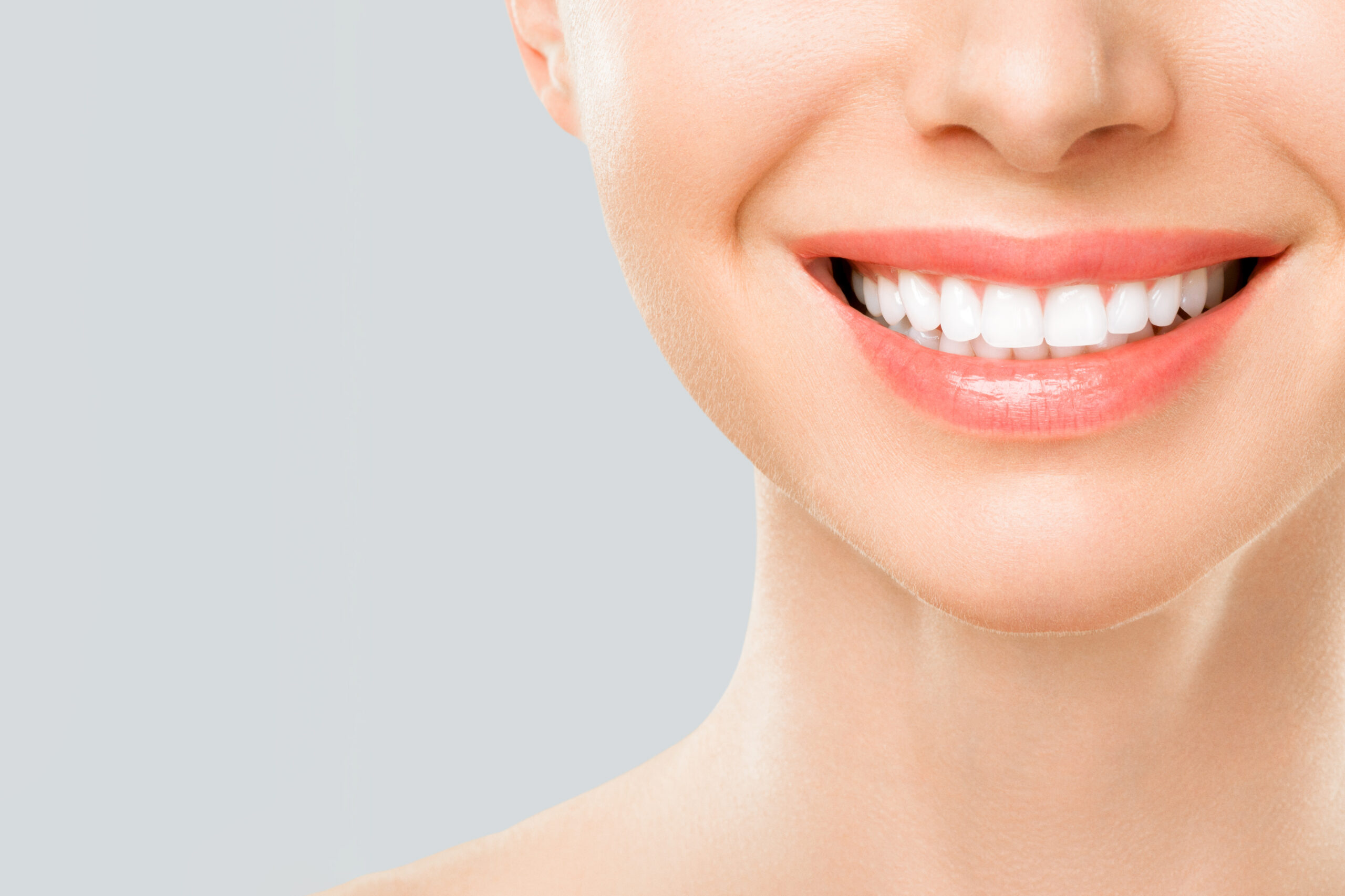 Perfect white teeth smile of a young woman. The result of the teeth whitening procedure. The image symbolizes oral care dentistry, Closeup on a white background.